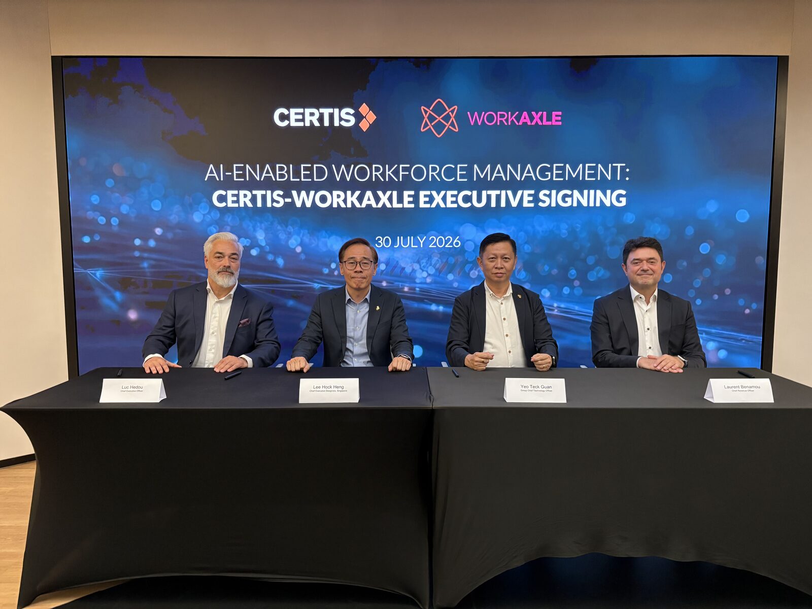 Quatre dirigeants assis &agrave; la table de signature devant un &eacute;cran affichant AI-Enabled Workforce Management&nbsp;: Certis-WorkAxle Executive Signing, 30 July 2026.